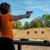 Beginner woman aiming pistol at indoor range