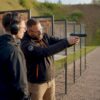 Shooting instructor instructing beginner inside range
