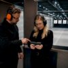 Instructor guiding visitor inside indoor shooting range