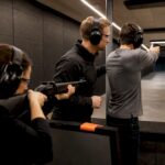 Instructor comparing rifle and pistol handling indoors