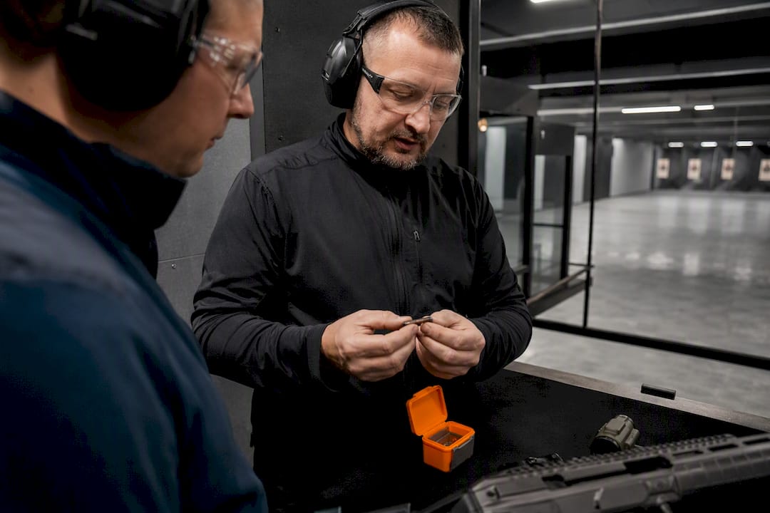 Instructor checking optic battery indoors