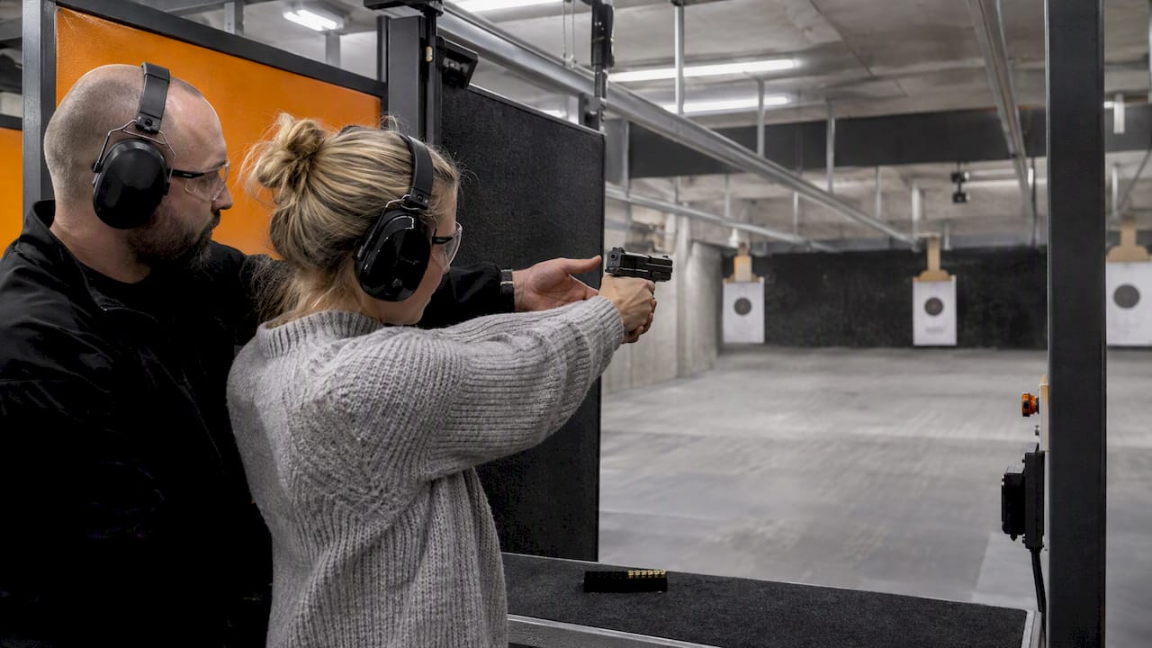 Instructor guiding a beginner at an indoor range